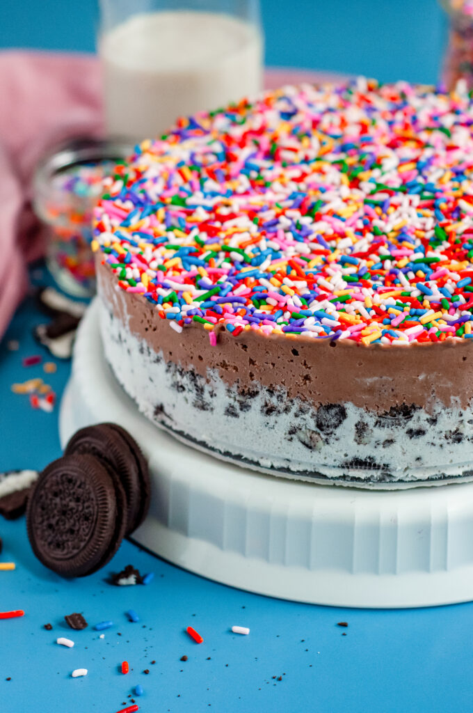 Ice Cream cake with and Oreo crust bottom covered in rainbow sprinkles.