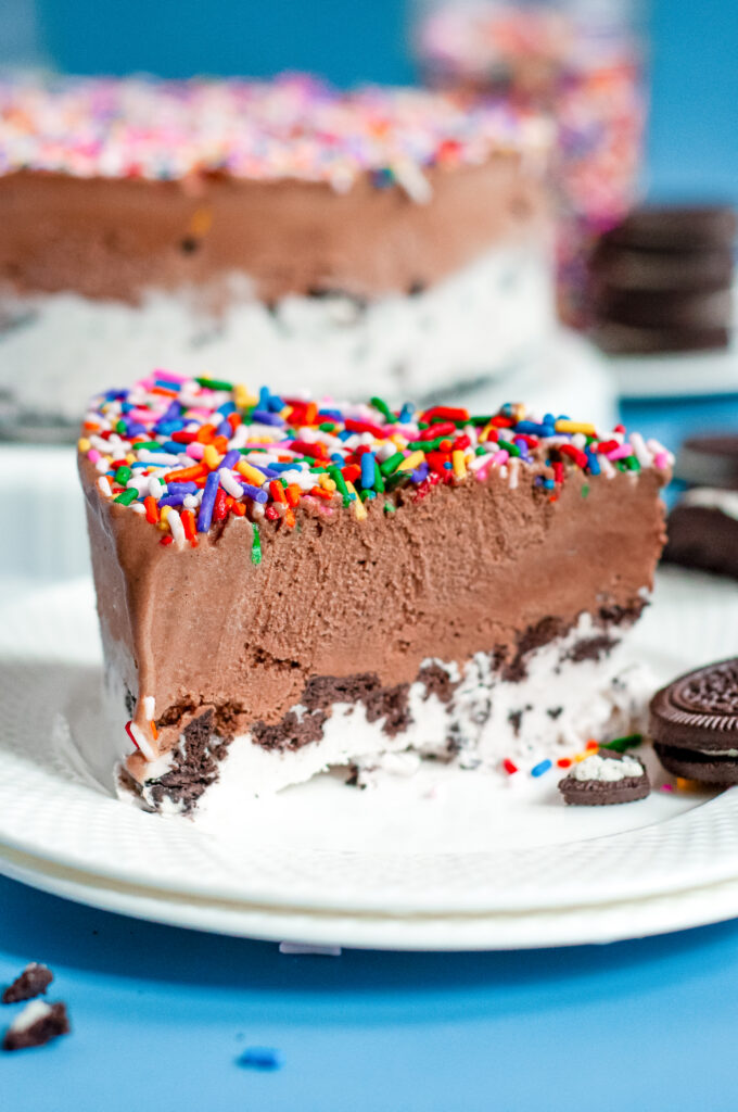 Slice of Ice Cream cake with and Oreo crust bottom covered in rainbow sprinkles.