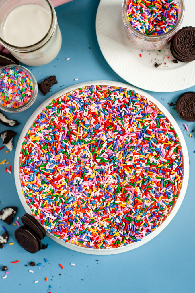 The top of an Ice Cream cake with and Oreo crust bottom covered in rainbow sprinkles.