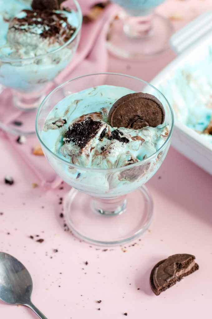 A square slice of Cookie Monster Icebox Dessert showing layers of Oreos, pudding, blue whipped topping, and Chips Ahoy cookies with sprinkles.