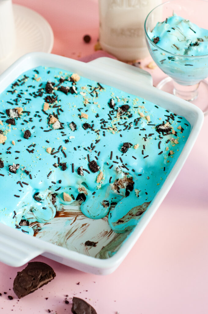 A square slice of Cookie Monster Icebox Dessert showing layers of Oreos, pudding, blue whipped topping, and Chips Ahoy cookies with sprinkles.