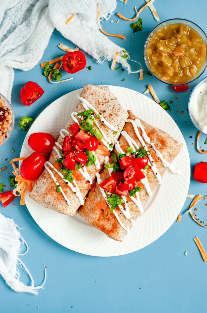 Air Fryer Chicken Chimichangas topped with tomatoes and sour cream on a plate.