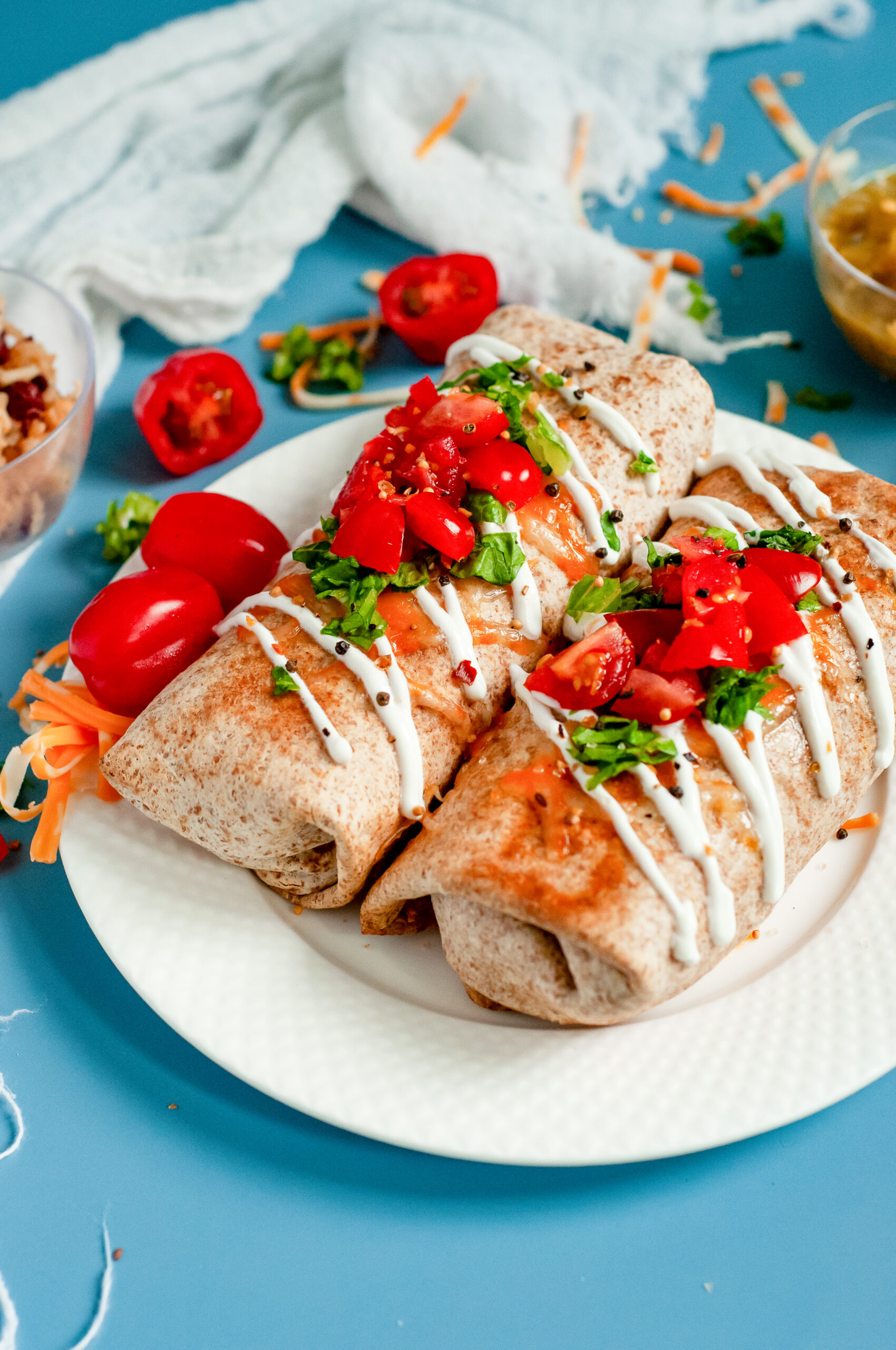 Air Fryer Chicken Chimichangas topped with tomatoes and sour cream on a plate.