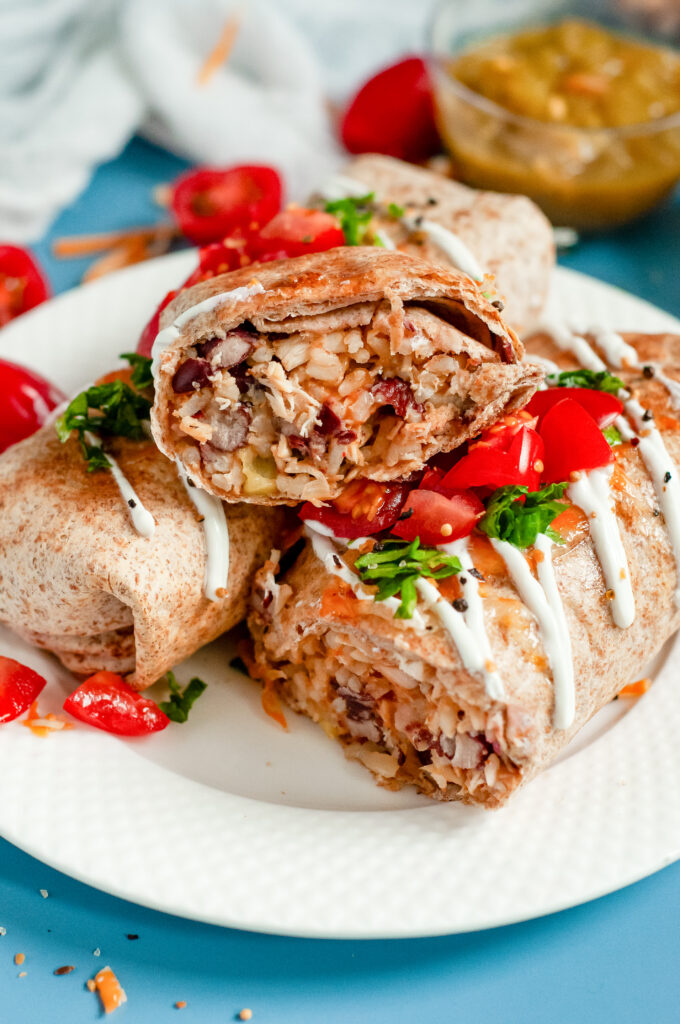 Air Fryer Chicken Chimichangas topped with tomatoes and sour cream on a plate.