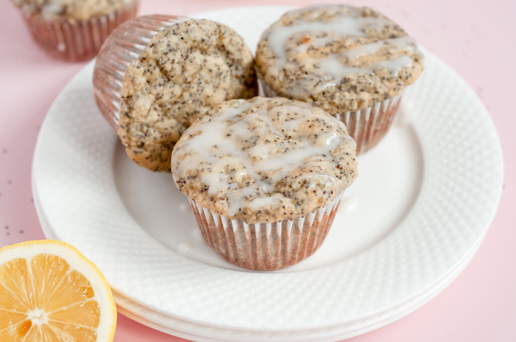 A batch of golden Lemony Sunshine Chia Muffins with a light, fluffy texture, speckled with chia seeds, and topped with a vibrant lemon glaze.