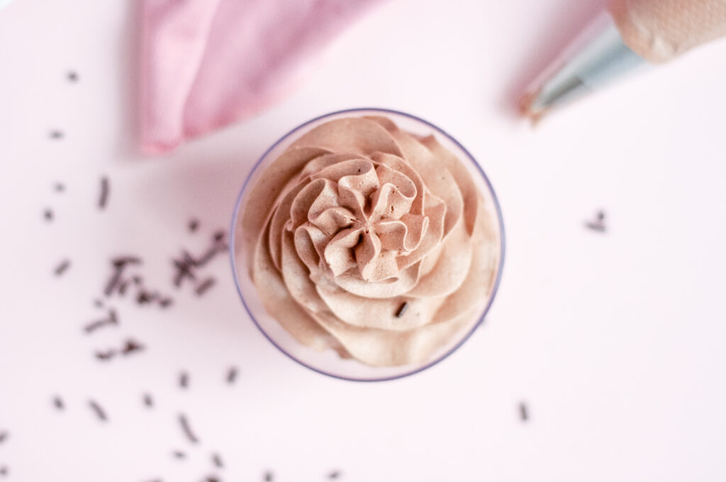 A bowl of smooth, rich chocolate buttercream frosting ready to be spread on a cake.