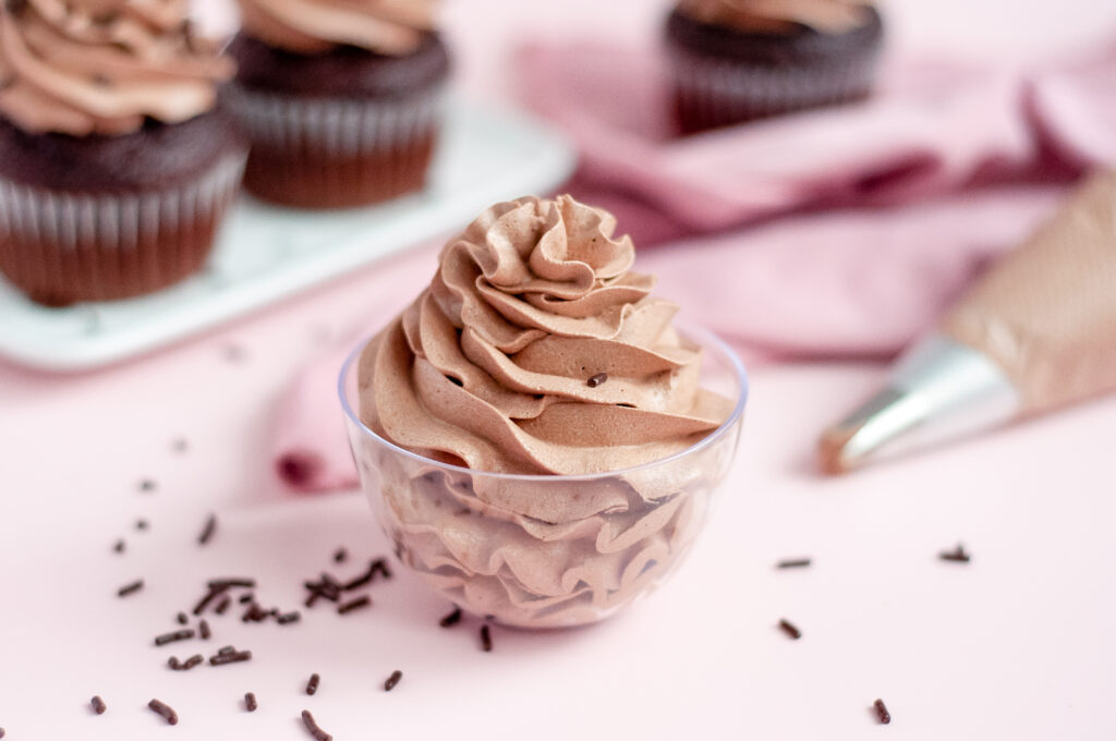 A bowl of smooth, rich chocolate buttercream frosting ready to be spread on a cake.