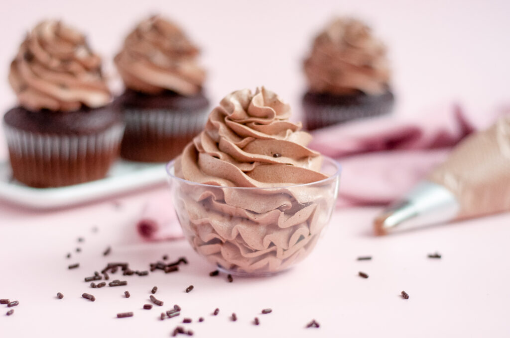 A bowl of smooth, rich chocolate buttercream frosting ready to be spread on a cake.