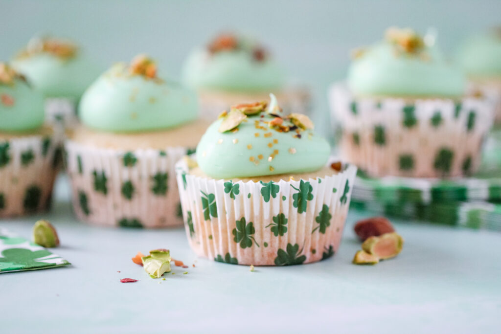 Almond cupcakes in St. Patrick’s Day liners, topped with green pistachio frosting and crushed pistachios.