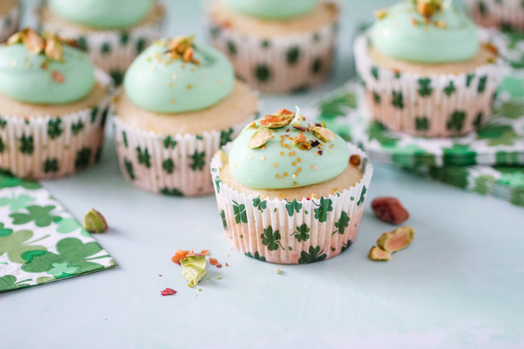 Almond cupcakes in St. Patrick’s Day liners, topped with green pistachio frosting and crushed pistachios.