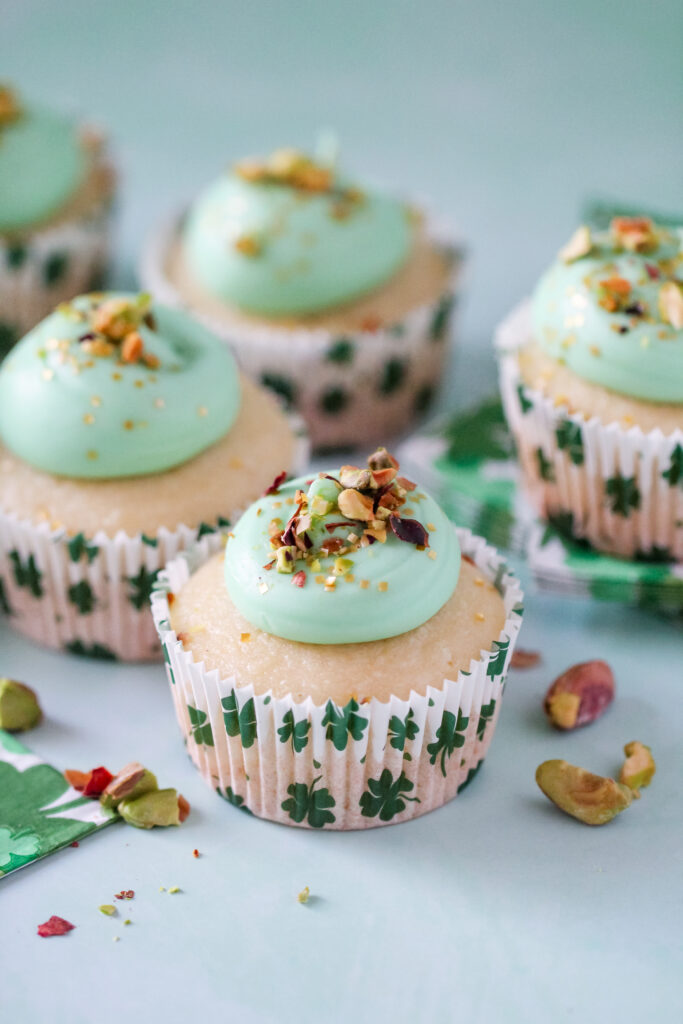 Almond cupcakes in St. Patrick’s Day liners, topped with green pistachio frosting and crushed pistachios.