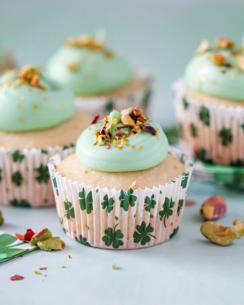 Almond cupcakes in St. Patrick’s Day liners, topped with green pistachio frosting and crushed pistachios.