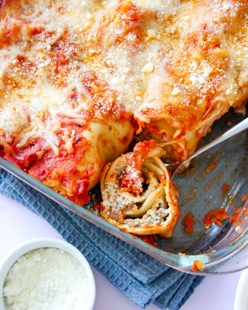 Cheesy baked lasagna rolls topped with marinara sauce and fresh basil