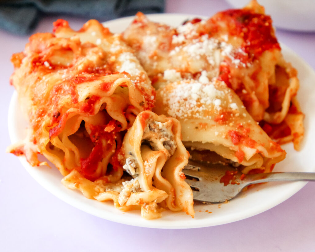 Cheesy baked lasagna rolls topped with marinara sauce and fresh basil