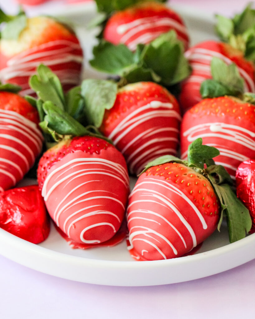 Red velvet chocolate-covered strawberries with a white chocolate drizzle, arranged on parchment paper – a vibrant, sweet treat perfect for any celebration.