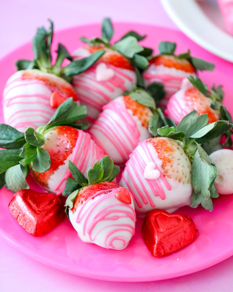 Close-up of white chocolate-dipped strawberries with edible glitter and heart decorations for Valentine’s Day.