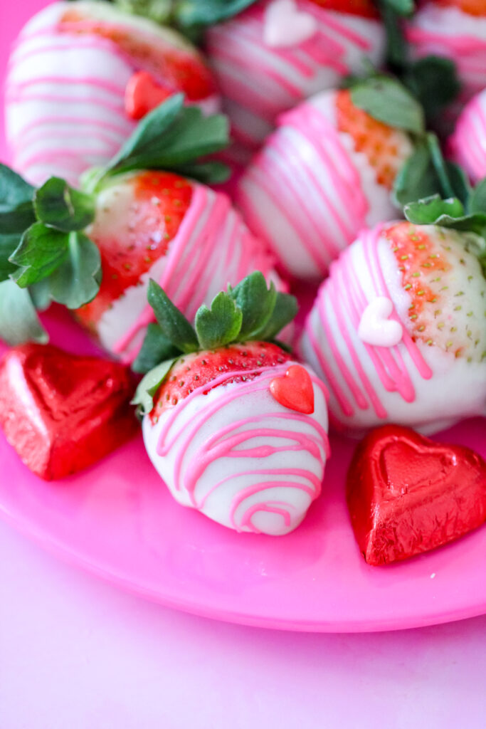 Close-up of white chocolate-dipped strawberries with edible glitter and heart decorations for Valentine’s Day.