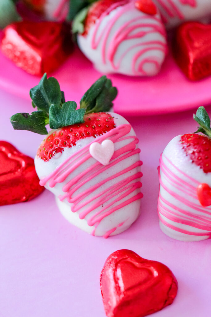 Close-up of white chocolate-dipped strawberries with edible glitter and heart decorations for Valentine’s Day.