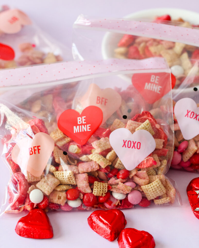 Bowl of Strawberry Chex Snack Mix with pink and red M&Ms, white chocolate pretzels, and freeze-dried strawberries – a festive, crunchy snack.