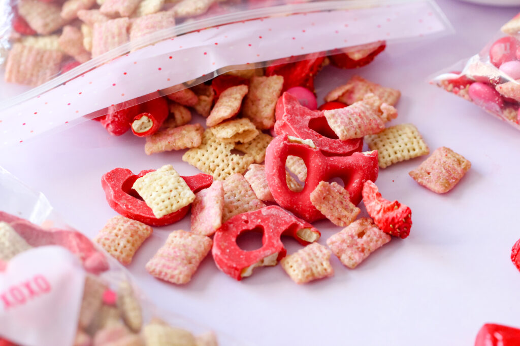 Bowl of Strawberry Chex Snack Mix with pink and red M&Ms, white chocolate pretzels, and freeze-dried strawberries – a festive, crunchy snack.