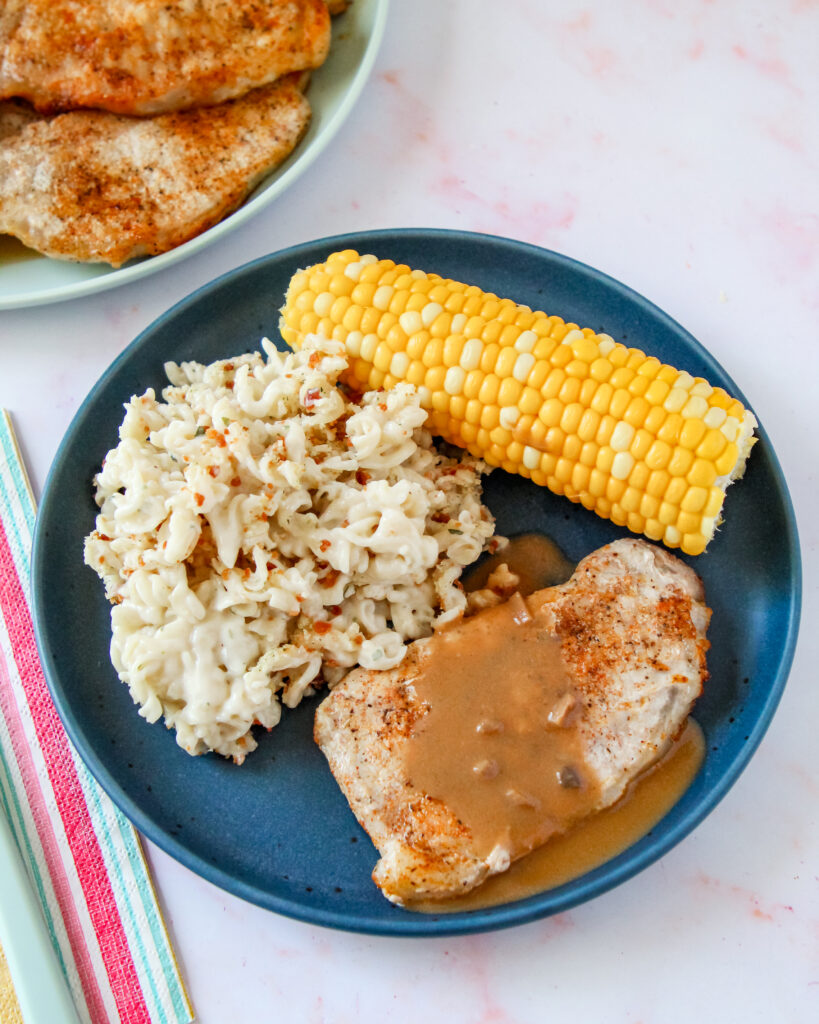 Golden air fryer pork chops topped with rich mushroom gravy, served over mashed potatoes with roasted vegetables in a cozy dinner bowl.