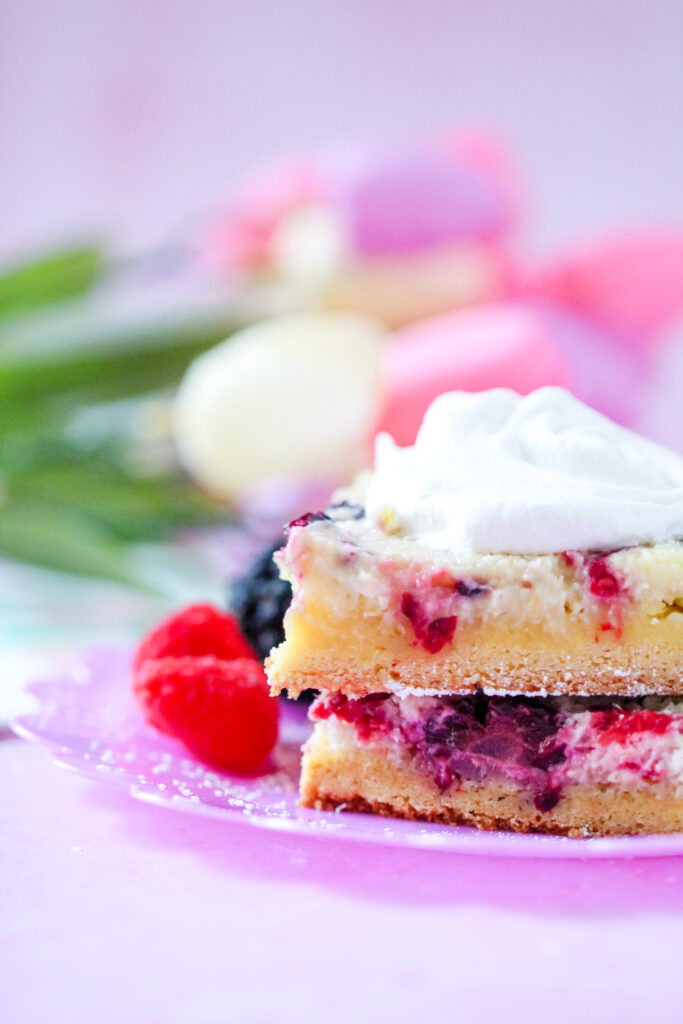 Close-up of a slice of Lemon Berry Gooey Butter Cake with a golden crust and creamy berry filling.