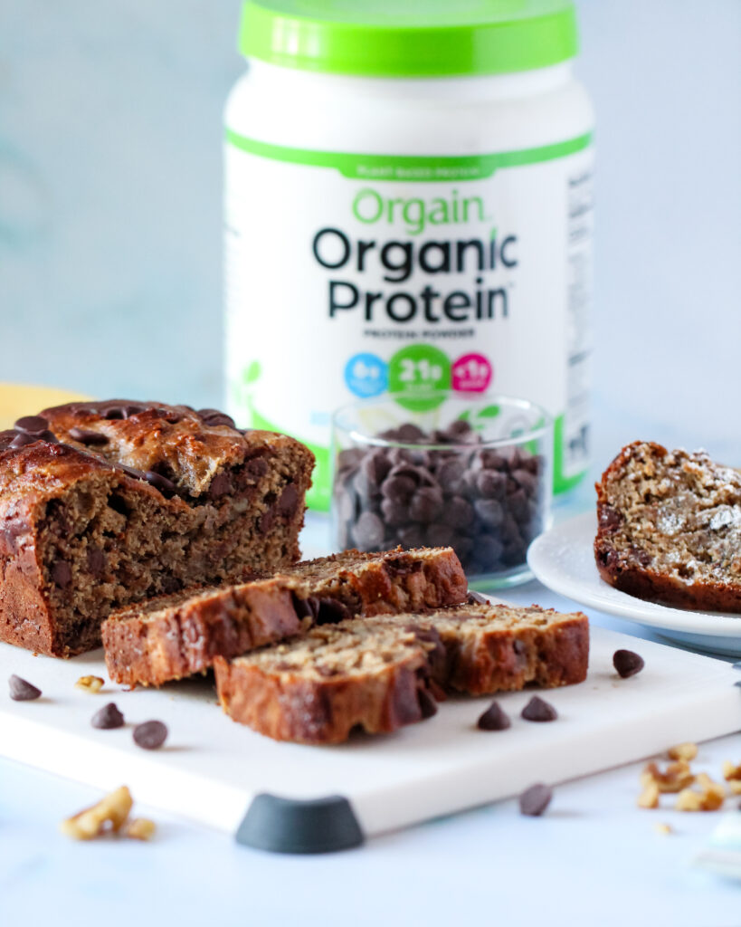 Sliced protein chocolate walnut banana bread on a cutting board, showcasing its moist texture and crunchy walnuts.