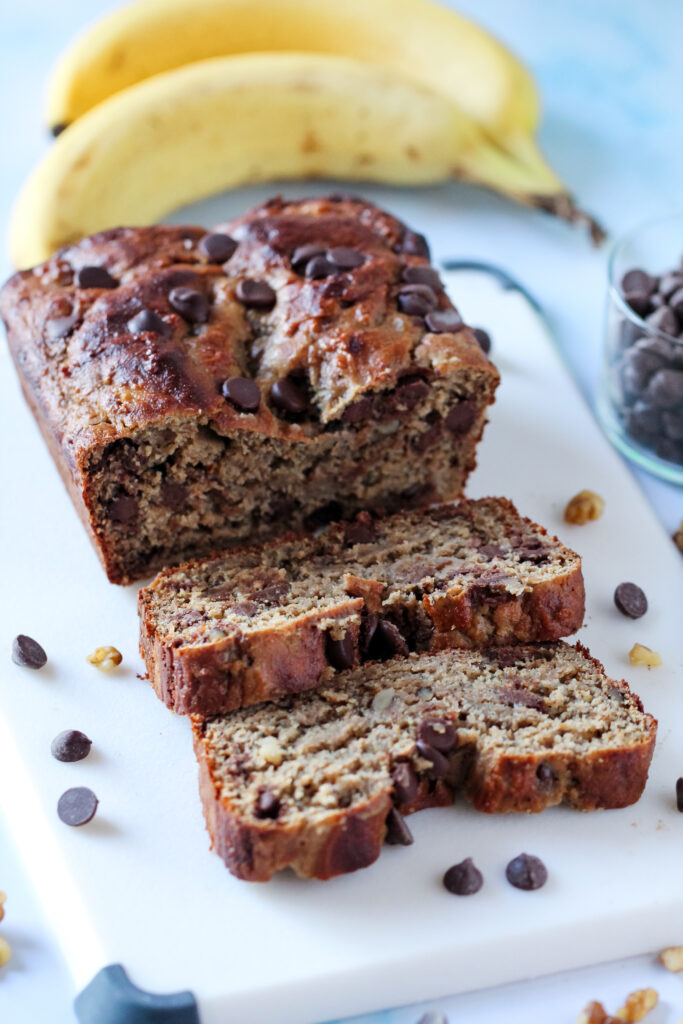 A close-up of a thick slice of chocolate walnut protein banana bread with melty chocolate chips.