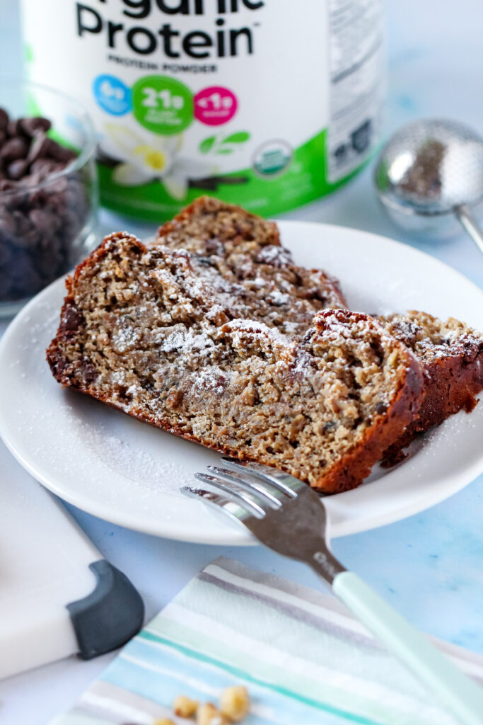 A close-up of a thick slice of chocolate walnut protein banana bread with melty chocolate chips.