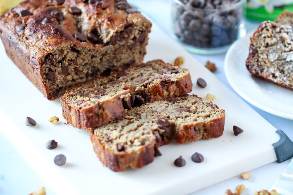 A close-up of a thick slice of chocolate walnut protein banana bread with melty chocolate chips.