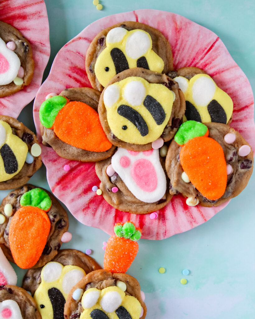 Cookies lined up on a parchment-lined baking sheet, each featuring a different marshmallow shape like flowers, bunnies, and bees.