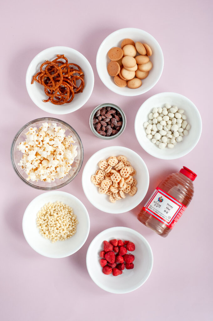 A bowl of honey bee snack mix with popcorn, pretzels, yogurt raisins, almonds, and white chocolate drizzle
