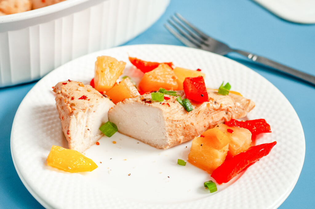 Colorful Hawaiian chicken cooked in a sticky pineapple-chili sauce with bell peppers and pineapple chunks served over white rice.