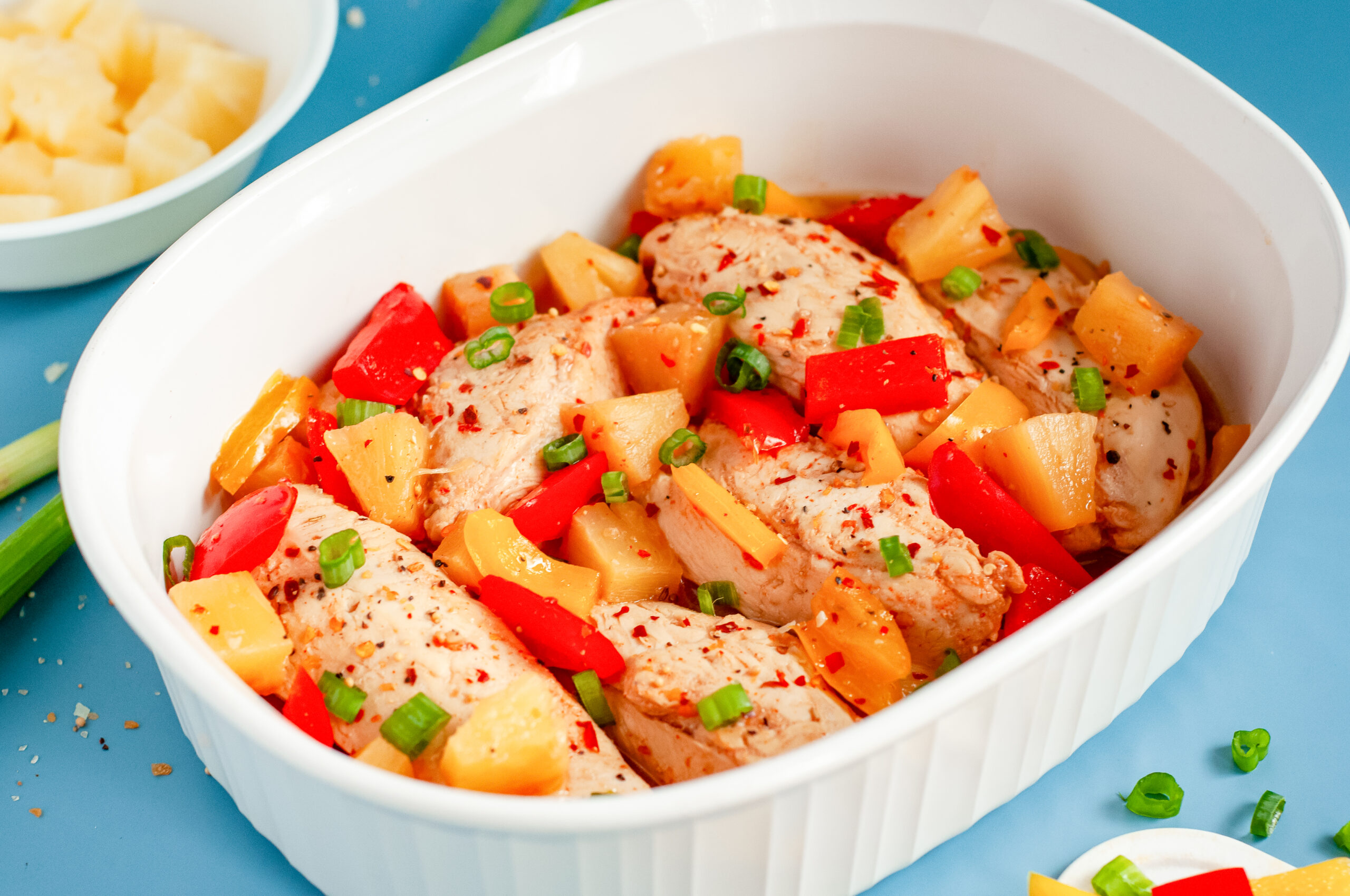 Colorful Hawaiian chicken cooked in a sticky pineapple-chili sauce with bell peppers and pineapple chunks served over white rice.
