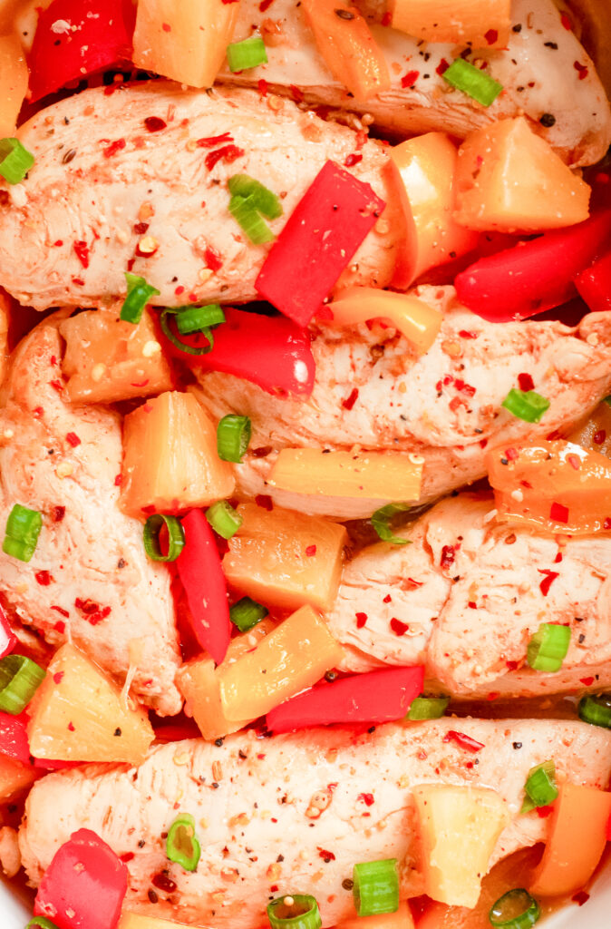 Colorful Hawaiian chicken cooked in a sticky pineapple-chili sauce with bell peppers and pineapple chunks served over white rice.