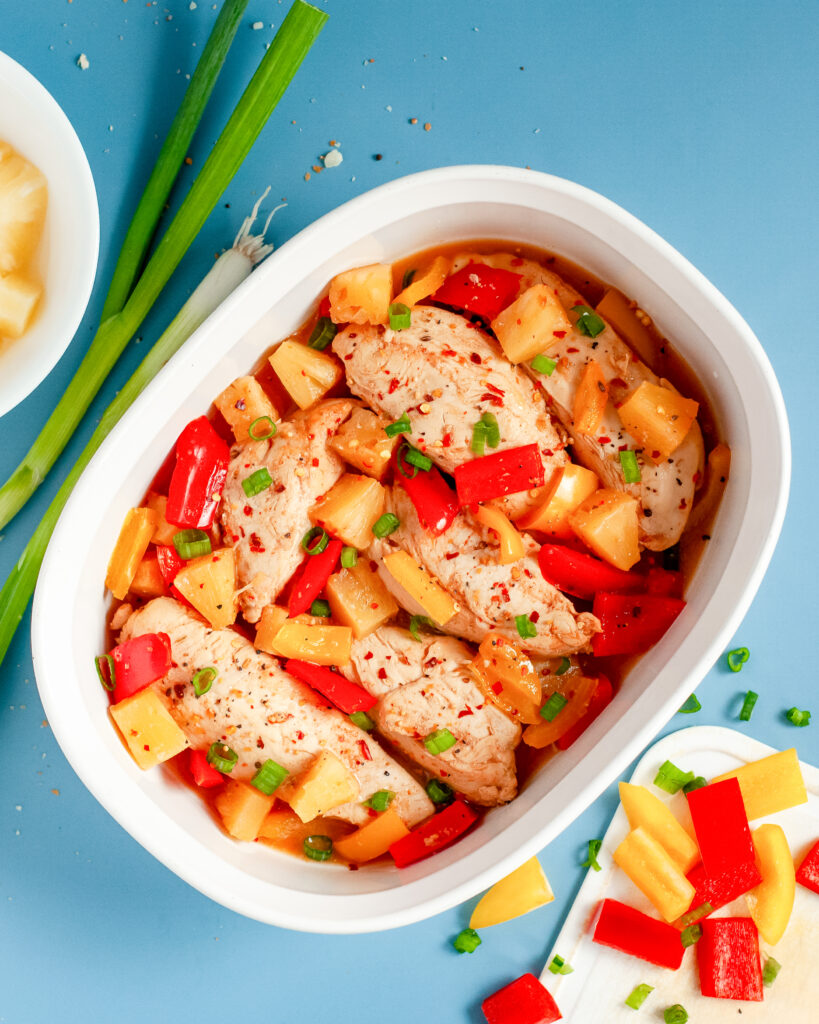 Colorful Hawaiian chicken cooked in a sticky pineapple-chili sauce with bell peppers and pineapple chunks served over white rice.