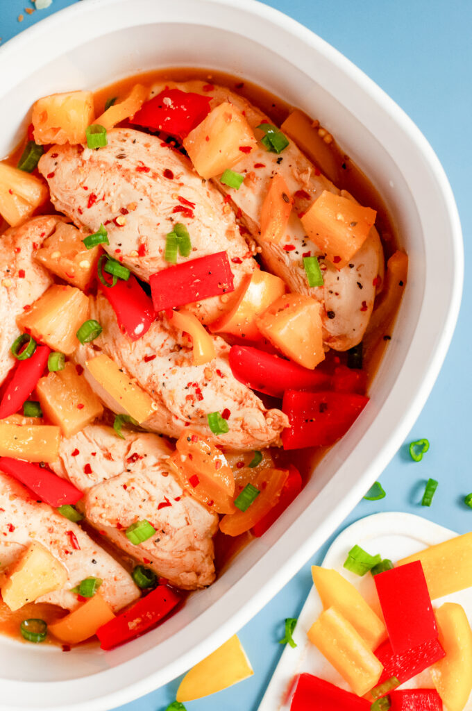 Colorful Hawaiian chicken cooked in a sticky pineapple-chili sauce with bell peppers and pineapple chunks served over white rice.