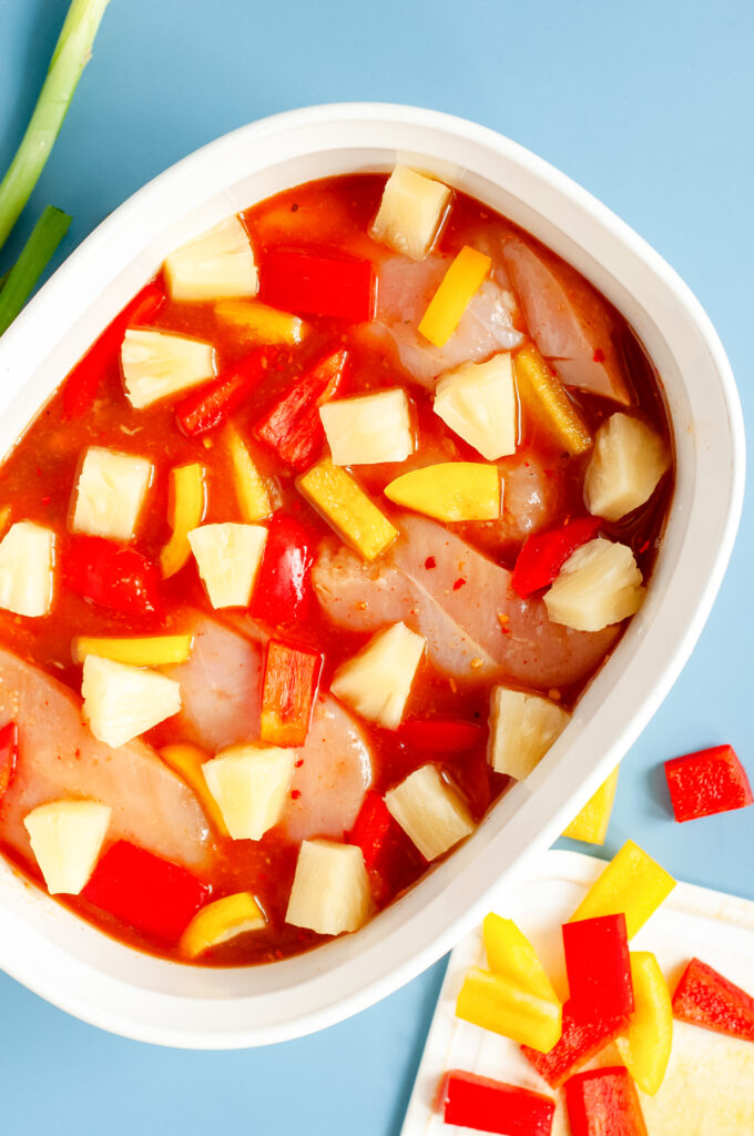 Colorful Hawaiian chicken cooked in a sticky pineapple-chili sauce with bell peppers and pineapple chunks served over white rice.