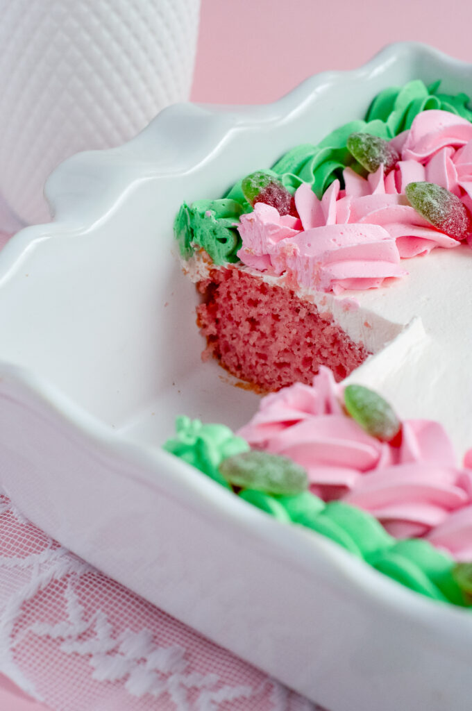 Decorated sheet cake with pink and green piped buttercream and sour strawberry candies, inspired by strawberry soda and vintage candy shop themes.