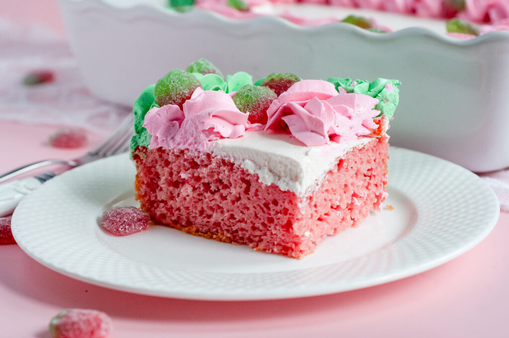 Decorated sheet cake with pink and green piped buttercream and sour strawberry candies, inspired by strawberry soda and vintage candy shop themes.