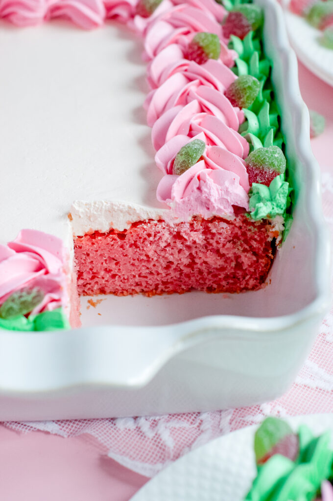 Decorated sheet cake with pink and green piped buttercream and sour strawberry candies, inspired by strawberry soda and vintage candy shop themes.