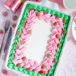 Decorated sheet cake with pink and green piped buttercream and sour strawberry candies, inspired by strawberry soda and vintage candy shop themes.