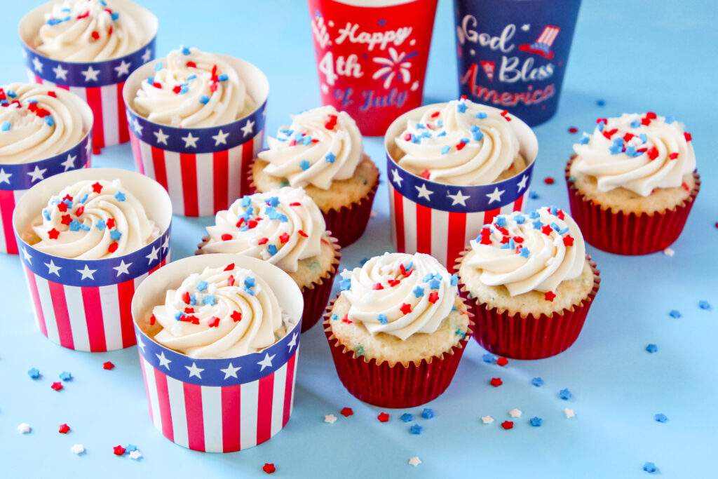 A batch of Patriotic Cupcakes perfect for Fourth of July with patriotic sprinkles on top of the frosting in a festive patriotic cupcake liners.