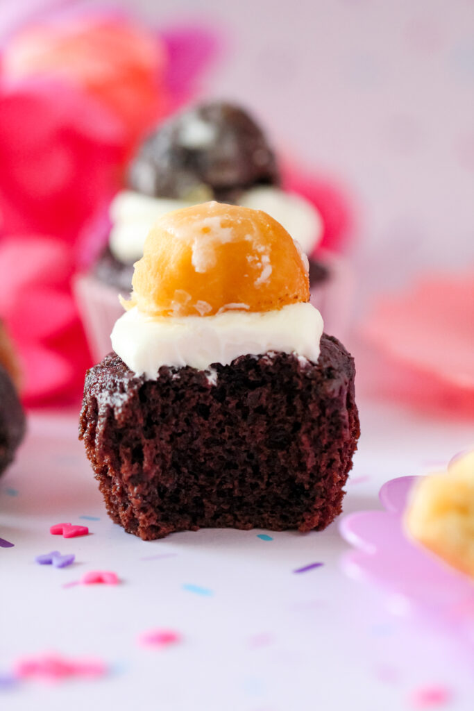 A chocolate cupcake with whipped vanilla donut frosting and donut decorations and munchkin donuts on top.
