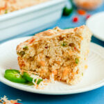 A slice of loaded cornbread with cheese, cornbread, and green onions using Dolly Parton's Cornbread Mix.