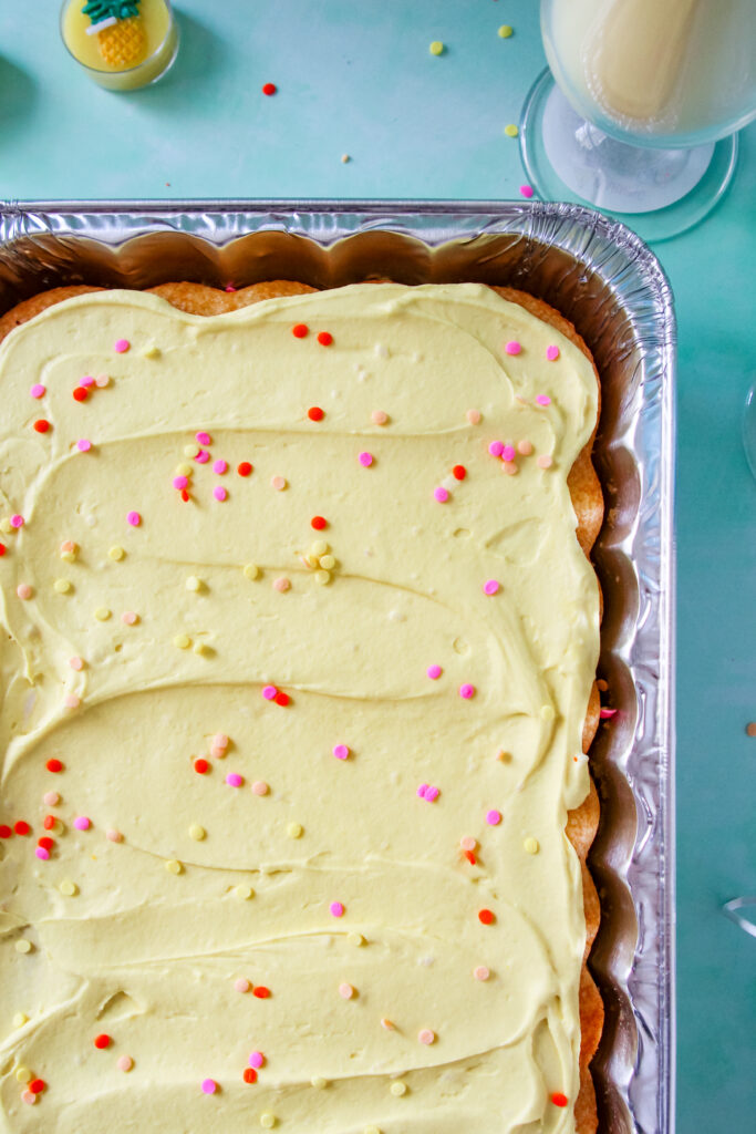 Pineapple Party Sheet Cake in a pan topped with sprinkles.
