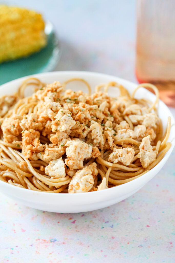 A bowl of seasoned ground chicken breast on top of pasta.