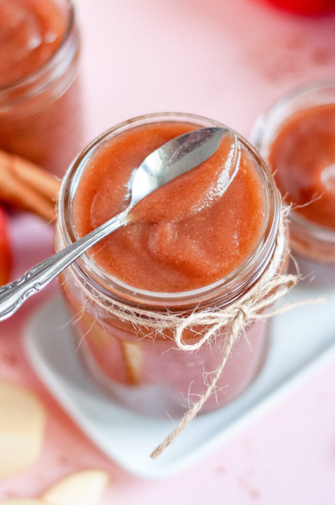 Top view of a jar of thick caramel-apple butter in a glass container, rich brown in color.