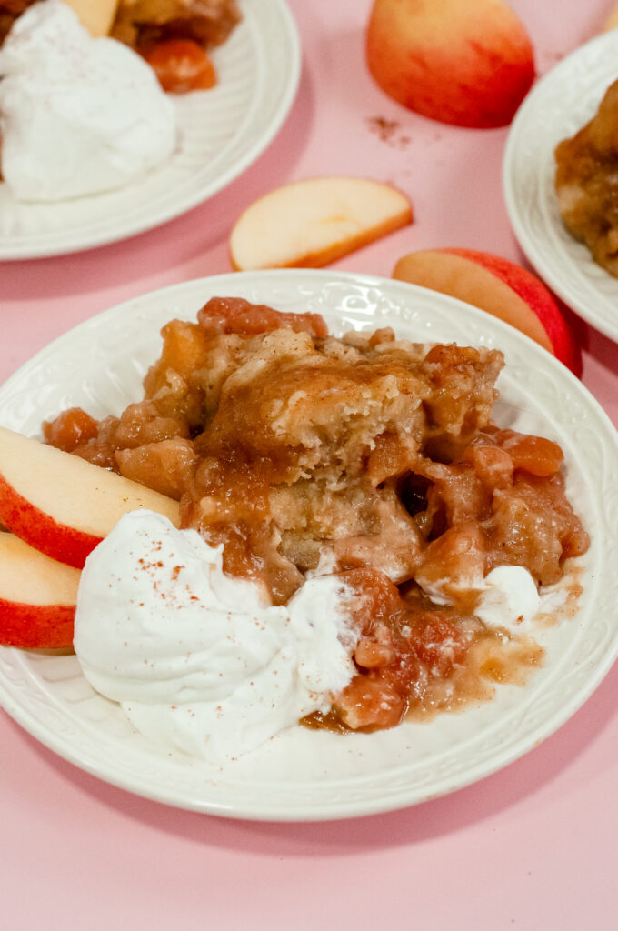 Caramel apple cake with whipped cream and apple slices.