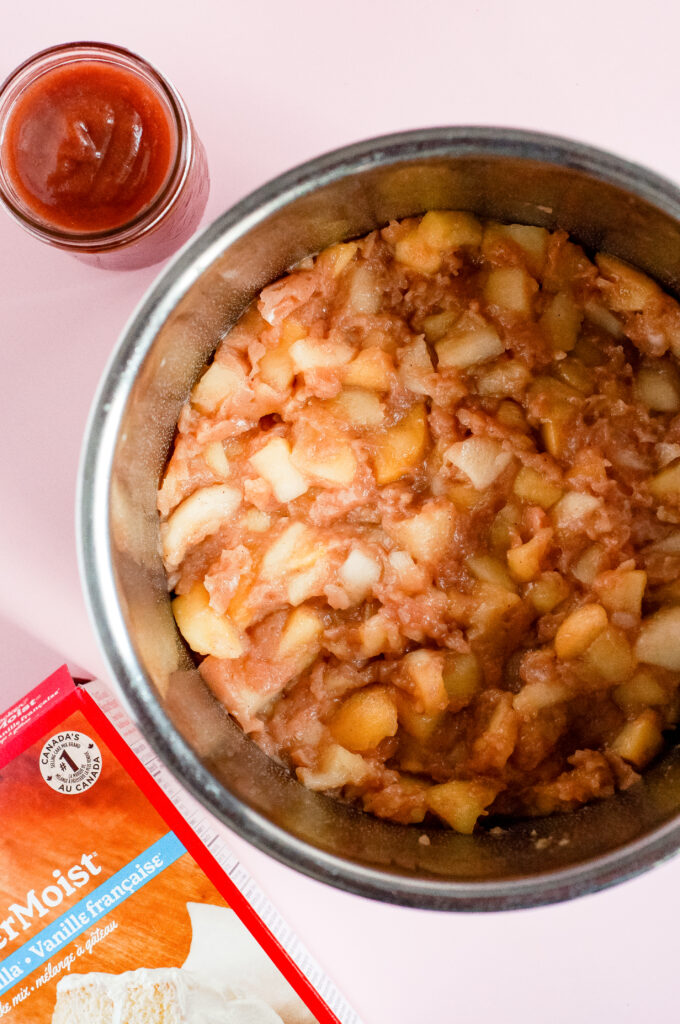 A image of apples in a bowl mixed with cake mix. 